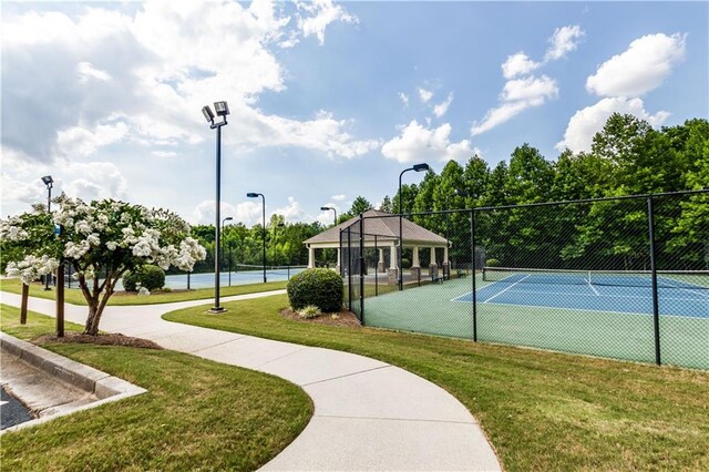 view of tennis court featuring a lawn