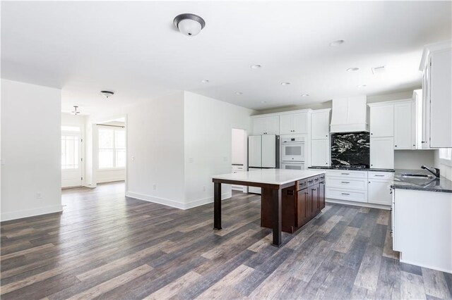 kitchen featuring custom range hood, a center island, dark hardwood / wood-style floors, and white cabinets