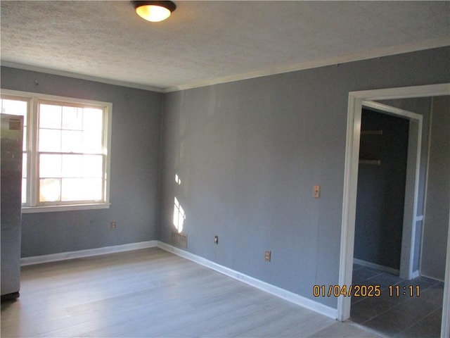 spare room with ornamental molding and light wood-type flooring