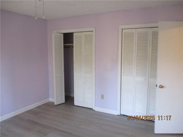 unfurnished bedroom with hardwood / wood-style floors and two closets