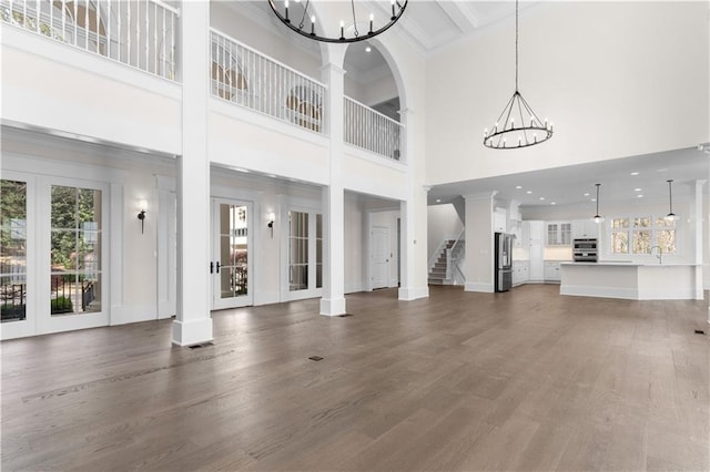 1070 Prosperity Pt, Greensboro, GA 30642 - unfurnished living room featuring a chandelier, healthy amount of natural light, crown molding, a high ceiling, and dark wood-style flooring