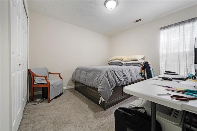 bedroom with a closet, light carpet, and a textured ceiling