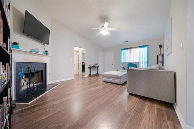 living room with hardwood / wood-style flooring, ceiling fan, vaulted ceiling, and a textured ceiling