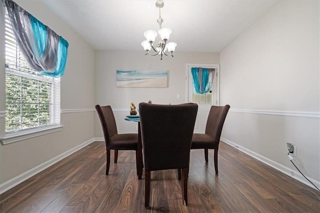 dining room with dark hardwood / wood-style floors and an inviting chandelier