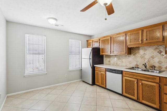 kitchen featuring dishwasher, backsplash, freestanding refrigerator, light countertops, and a sink