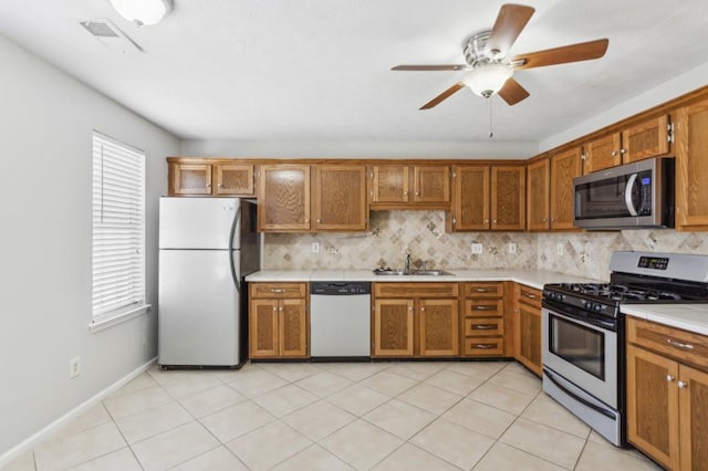 kitchen with brown cabinets, appliances with stainless steel finishes, a sink, and decorative backsplash