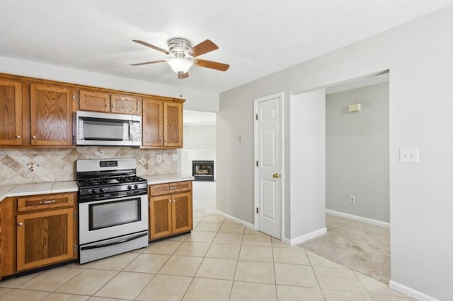 kitchen with stainless steel appliances, brown cabinetry, decorative backsplash, and light tile patterned flooring