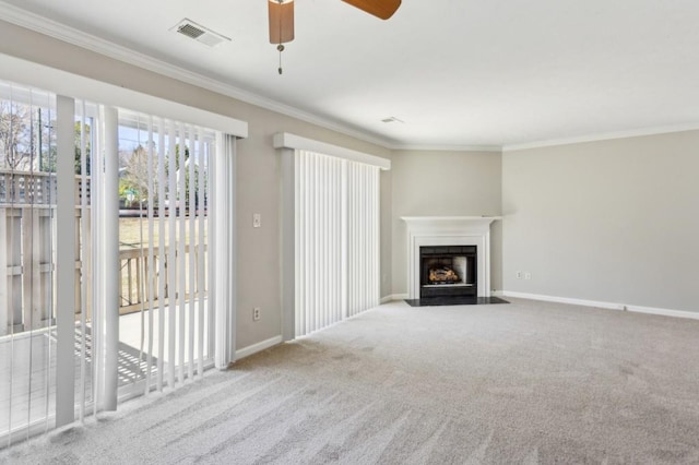 unfurnished living room with carpet floors, a fireplace with flush hearth, visible vents, baseboards, and crown molding