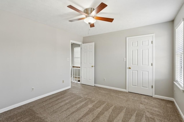 unfurnished bedroom with carpet floors, multiple windows, ceiling fan, and baseboards