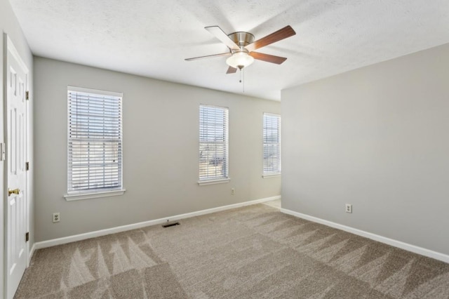 carpeted spare room featuring visible vents, ceiling fan, a textured ceiling, and baseboards