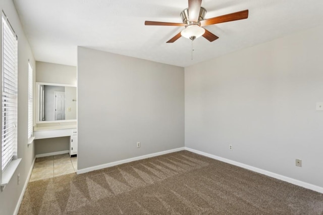 unfurnished bedroom featuring ceiling fan, built in desk, carpet flooring, and baseboards