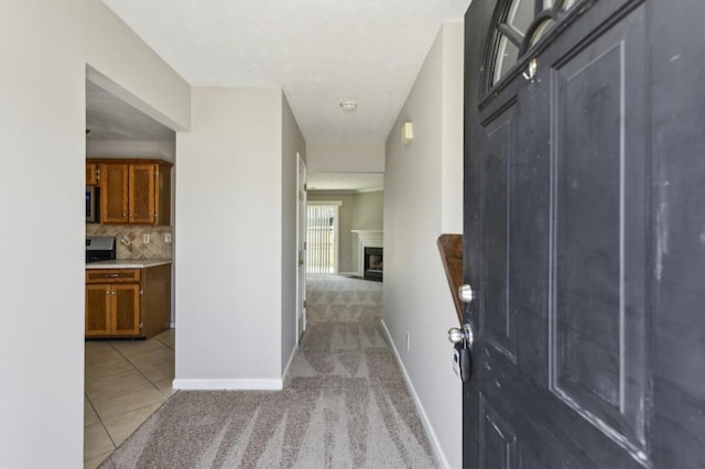 hall with light carpet, light tile patterned floors, and baseboards