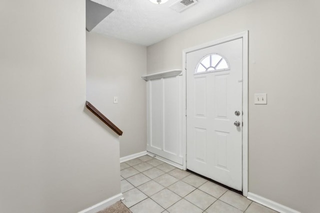 foyer entrance featuring light tile patterned floors, baseboards, visible vents, stairway, and a textured ceiling