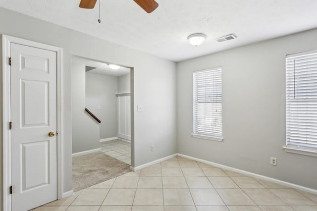 unfurnished room featuring light tile patterned floors, light colored carpet, visible vents, ceiling fan, and baseboards