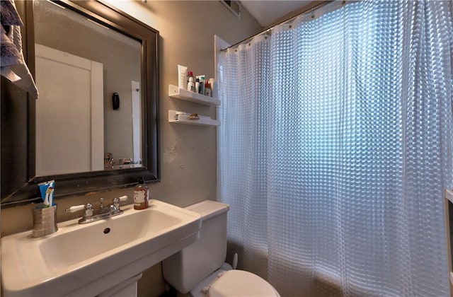 bathroom featuring walk in shower, sink, and toilet