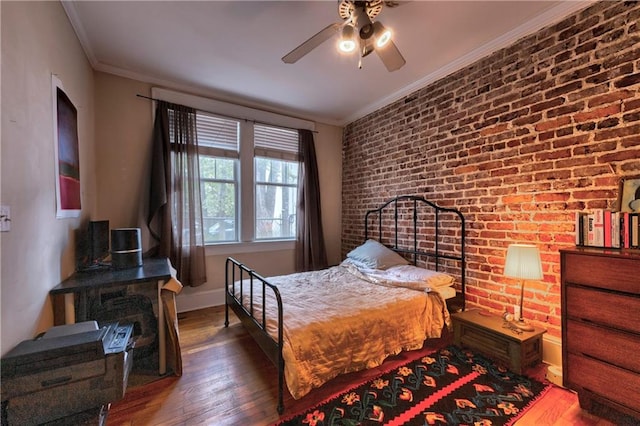 bedroom featuring ceiling fan, brick wall, crown molding, and hardwood / wood-style floors