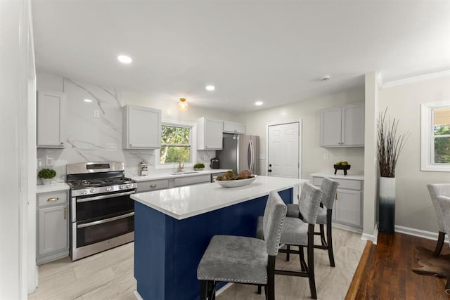 kitchen with a wealth of natural light, a center island, stainless steel appliances, and light hardwood / wood-style floors