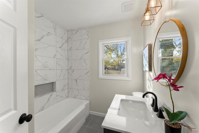 bathroom with tile patterned flooring, vanity, tiled shower / bath, and a wealth of natural light