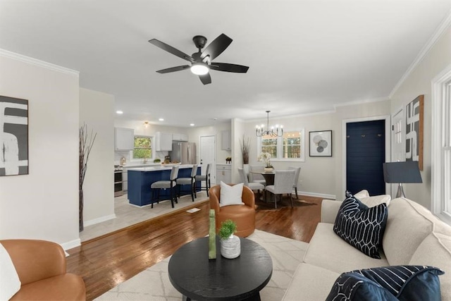 living room featuring light hardwood / wood-style flooring, ceiling fan with notable chandelier, and ornamental molding