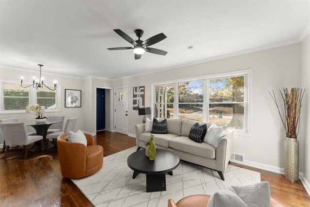 living room featuring hardwood / wood-style floors, ceiling fan with notable chandelier, and crown molding