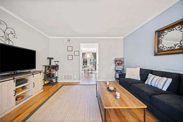 living room featuring light wood finished floors, visible vents, and crown molding