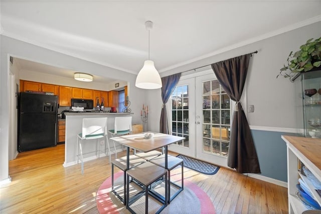 dining space featuring french doors, light wood finished floors, and ornamental molding