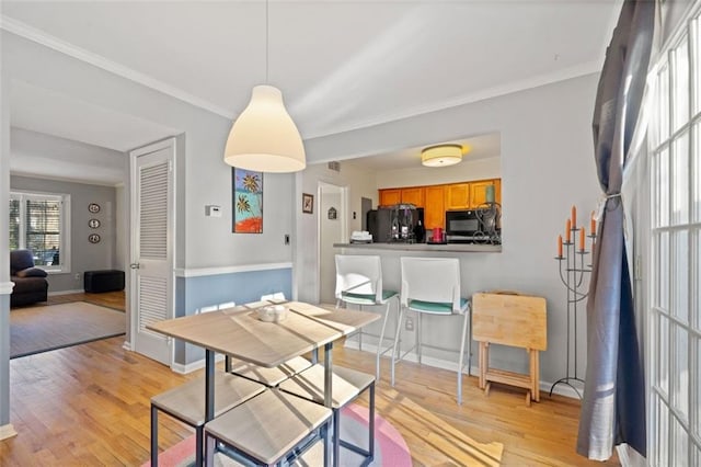 dining space with light wood finished floors, crown molding, and baseboards