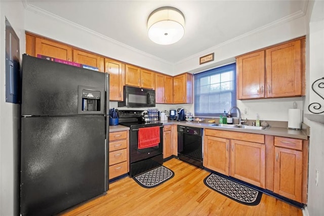 kitchen with a sink, light wood-style floors, black appliances, and crown molding