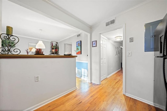 hall with ornamental molding, baseboards, visible vents, and light wood-type flooring