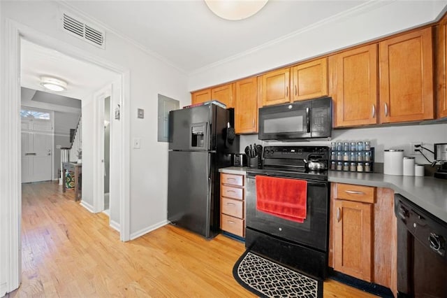 kitchen with visible vents, light wood-style flooring, black appliances, and ornamental molding