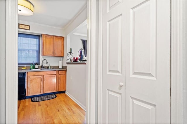 kitchen with dishwasher, light wood-type flooring, ornamental molding, brown cabinets, and a sink