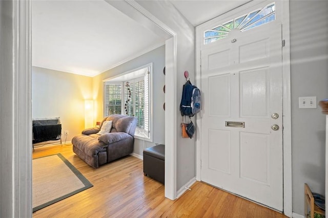 foyer with baseboards, light wood-style floors, and ornamental molding