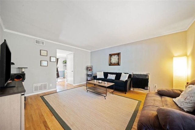 living room featuring crown molding, baseboards, visible vents, and light wood-type flooring