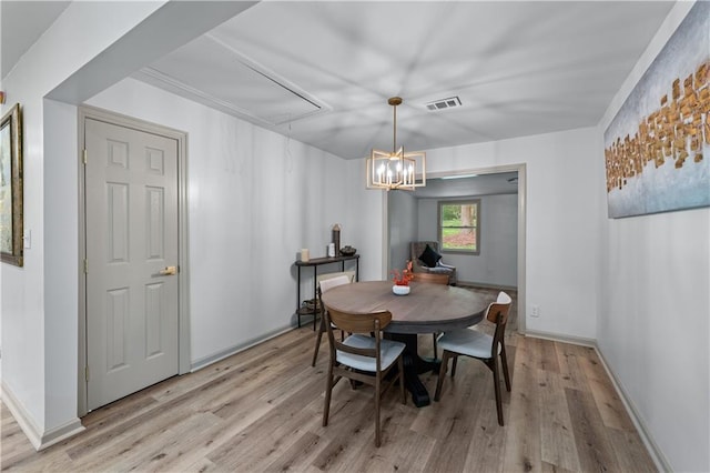 dining space featuring attic access, light wood-style flooring, and baseboards