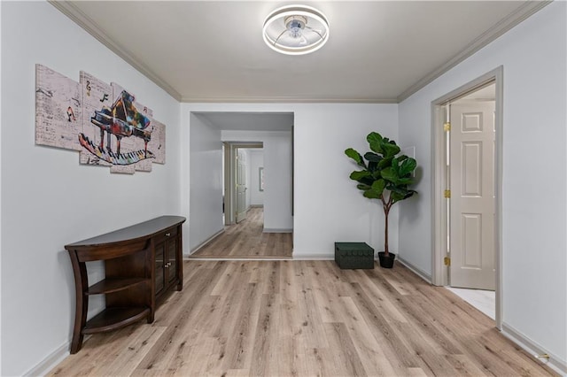 hall featuring light wood-type flooring, crown molding, and baseboards