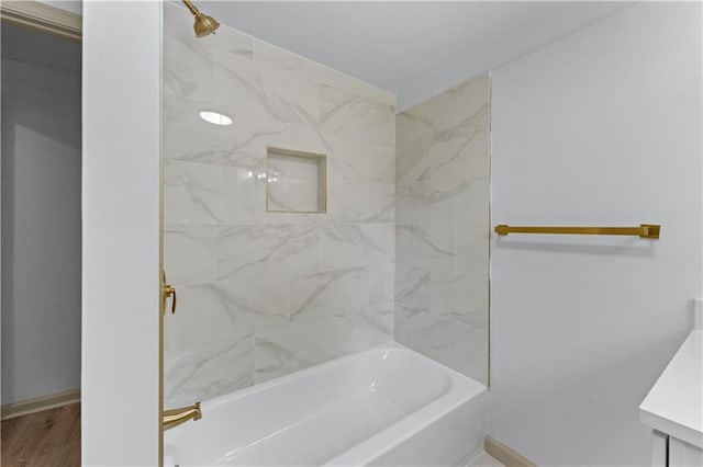 bathroom with bathing tub / shower combination, baseboards, and wood finished floors