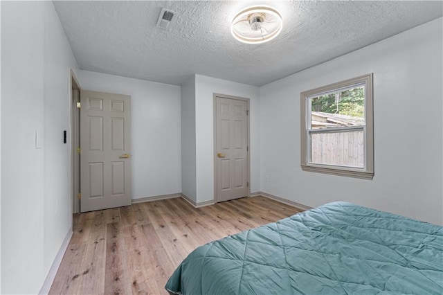 bedroom with a textured ceiling, wood finished floors, and baseboards