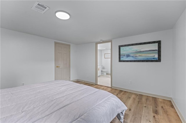 bedroom with light wood finished floors, baseboards, and ensuite bath