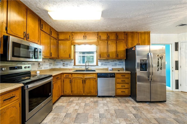 kitchen featuring brown cabinets, visible vents, stainless steel appliances, and a sink