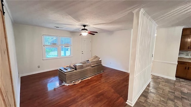 interior space featuring a ceiling fan, dark wood finished floors, visible vents, and baseboards