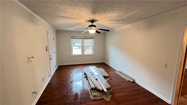 spare room with attic access, baseboards, a ceiling fan, dark wood-style flooring, and a textured ceiling