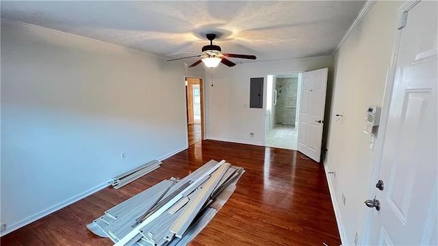 interior space featuring electric panel, crown molding, baseboards, and wood finished floors