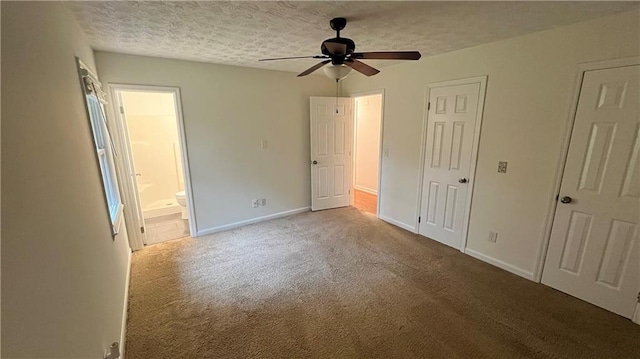 unfurnished bedroom featuring a textured ceiling, ceiling fan, ensuite bathroom, carpet flooring, and baseboards