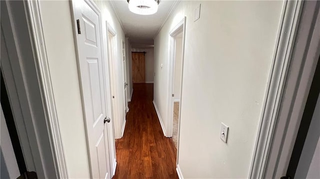 corridor featuring dark wood finished floors and baseboards