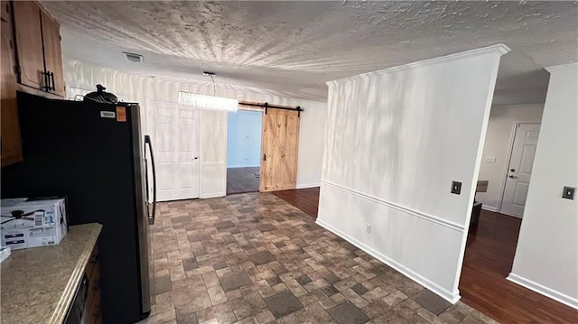 kitchen featuring freestanding refrigerator, visible vents, baseboards, and a barn door