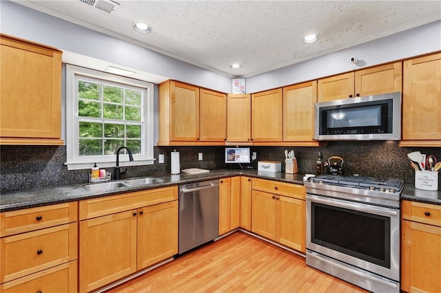 kitchen with visible vents, light wood-type flooring, a textured ceiling, a sink, and appliances with stainless steel finishes