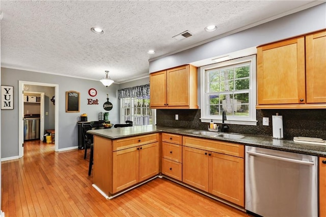 kitchen with a sink, dishwasher, a peninsula, backsplash, and visible vents