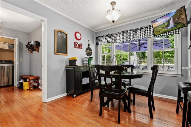 dining room with washer / clothes dryer, a textured ceiling, baseboards, and light wood-type flooring
