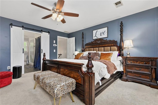 bedroom featuring ceiling fan, visible vents, a barn door, carpet floors, and ensuite bath