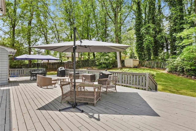 deck featuring an outdoor structure, outdoor dining area, a fenced backyard, a storage unit, and a yard